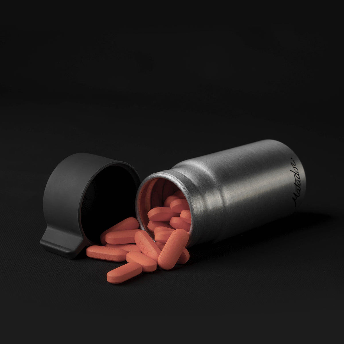 Canister full of orange pills on black background