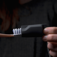 Hand putting black cap on toothbrush