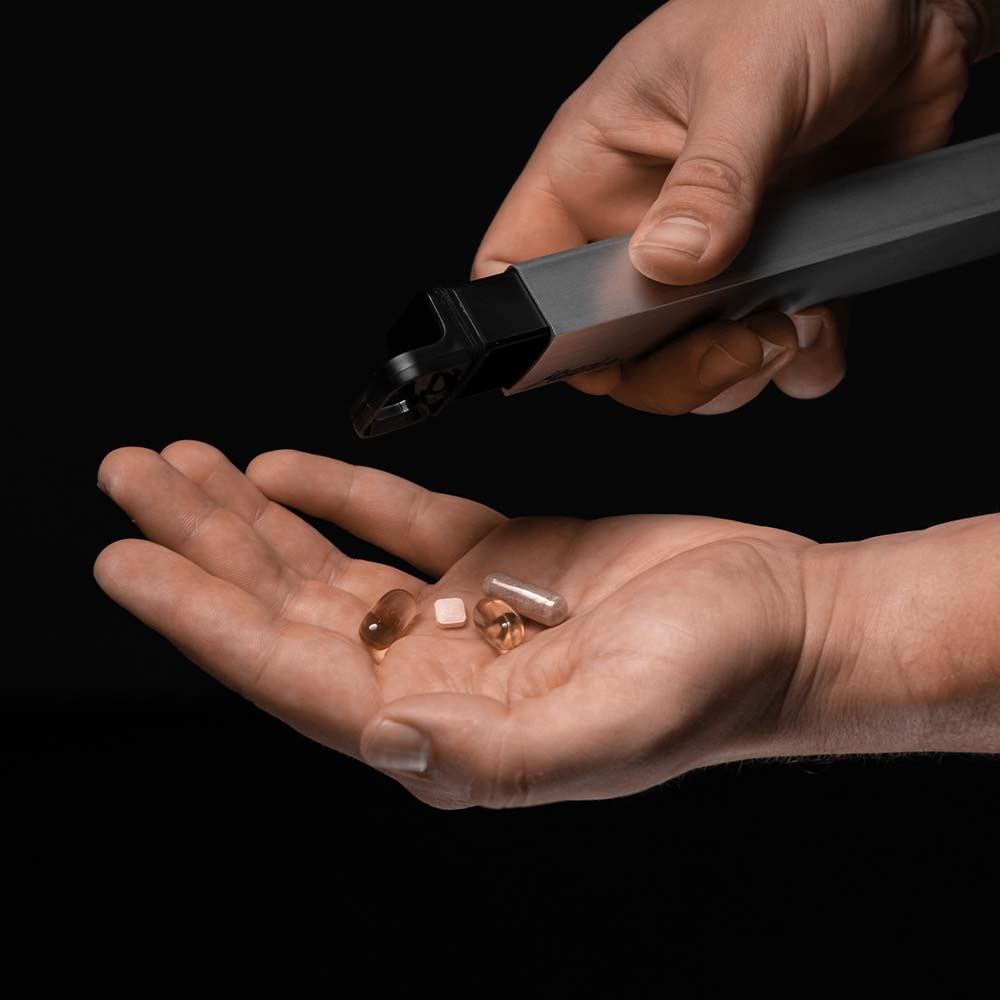 Man pouring pills out of canister compartment on black background