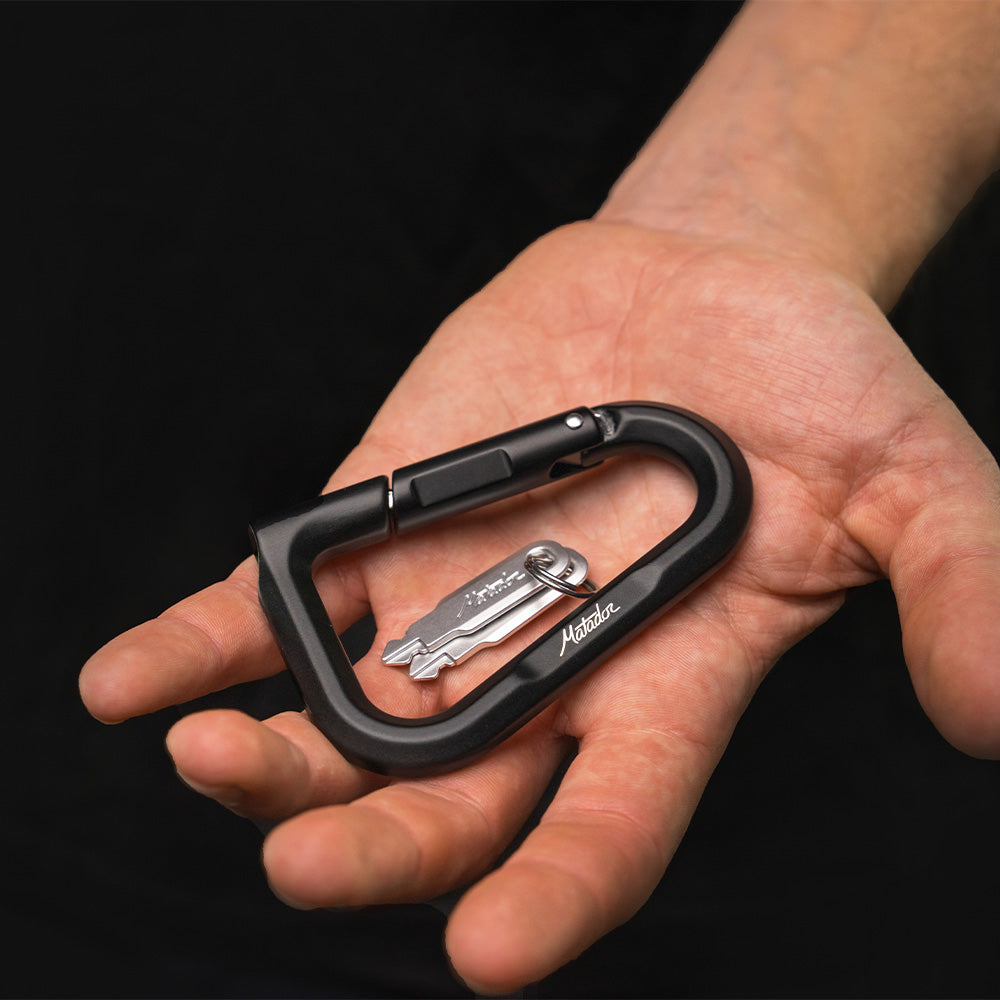 hand on black background holding black betalock and 2 keys