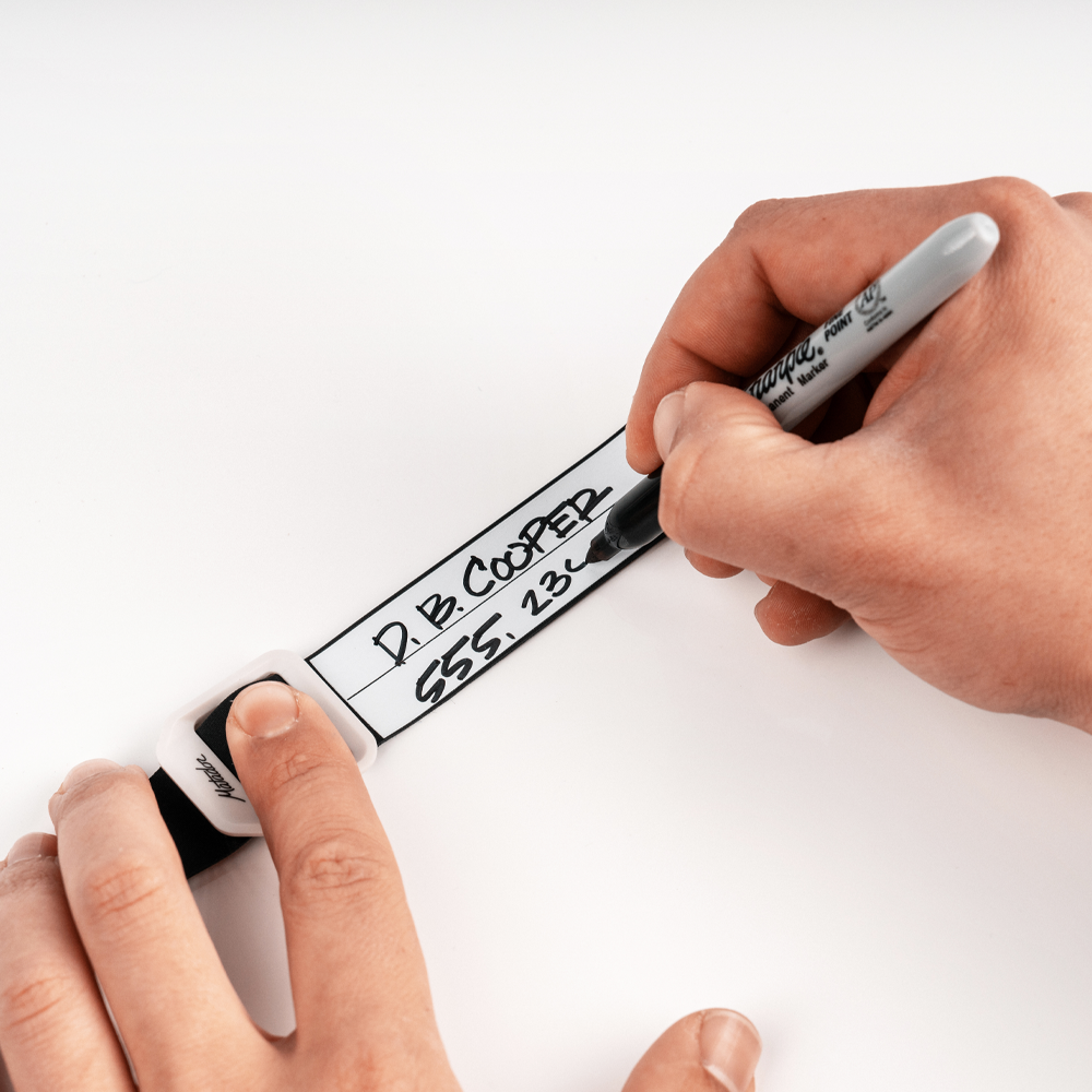 Hands on white background writing contact information onto gear tag with sharpie marker