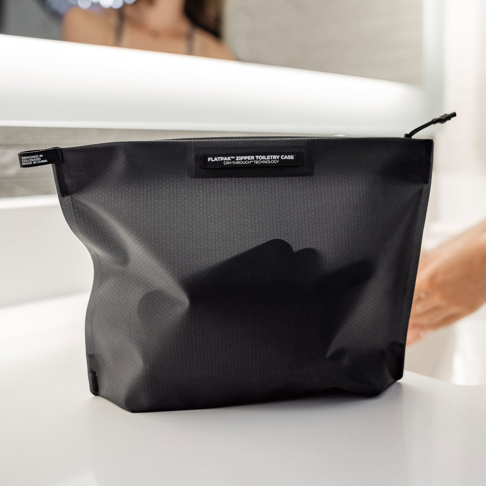 Toiletry case sitting on bathroom counter top with contents slightly visible through material