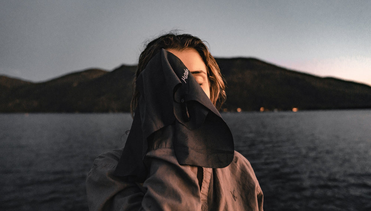 Woman at evening lake, drying her face with Nanodry Trek Towel