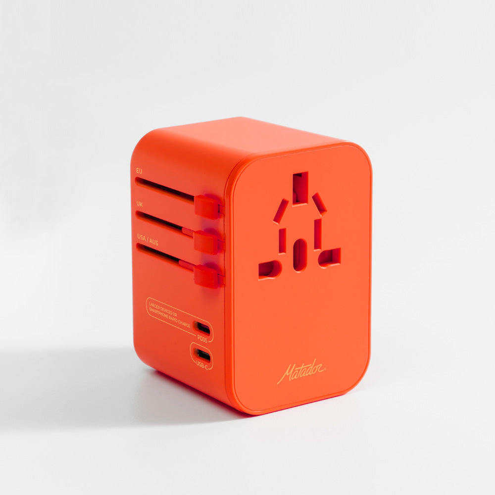 3/4 view of orange travel adapter on light gray background
