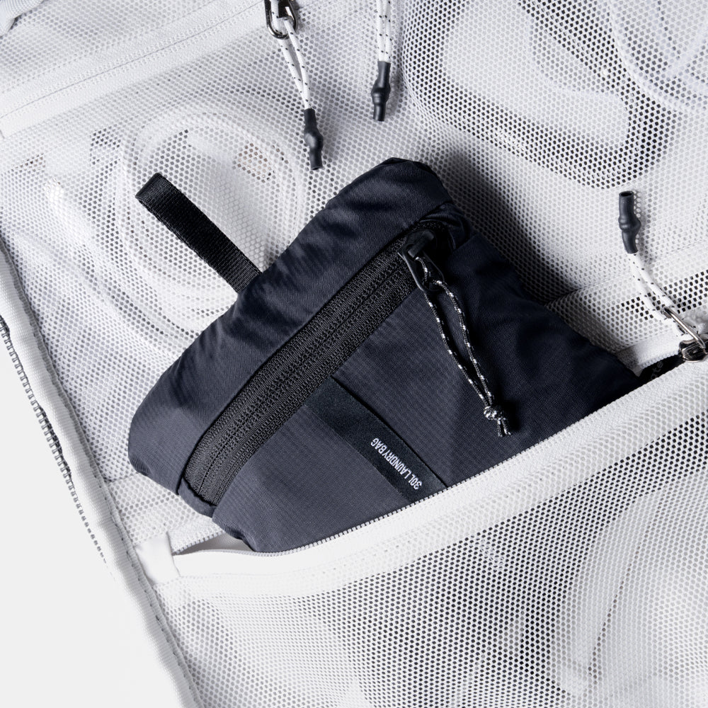 Packed up laundry bag, coming out of mesh zipper pocket of travel pack
