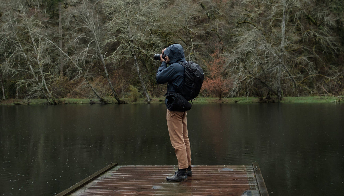 Man on rainy lake dock, taking a photo